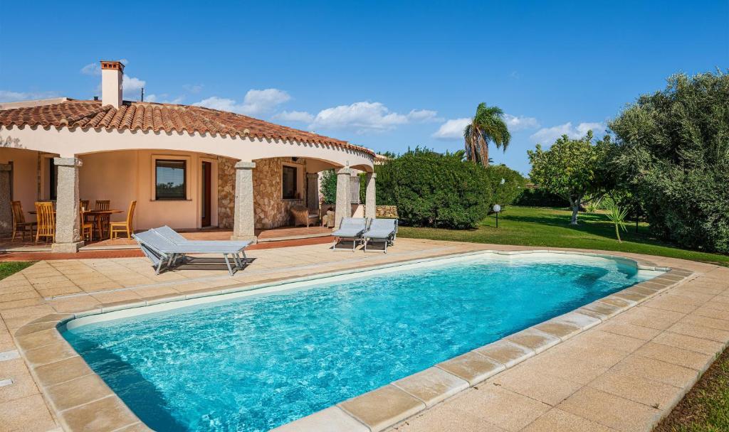 a swimming pool in front of a house at Villa Mistral in Costa Rei