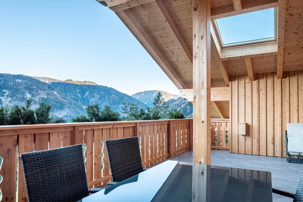 a deck with a table and chairs and mountains at Mittnackerhof Apartment Melisse in Sarntal