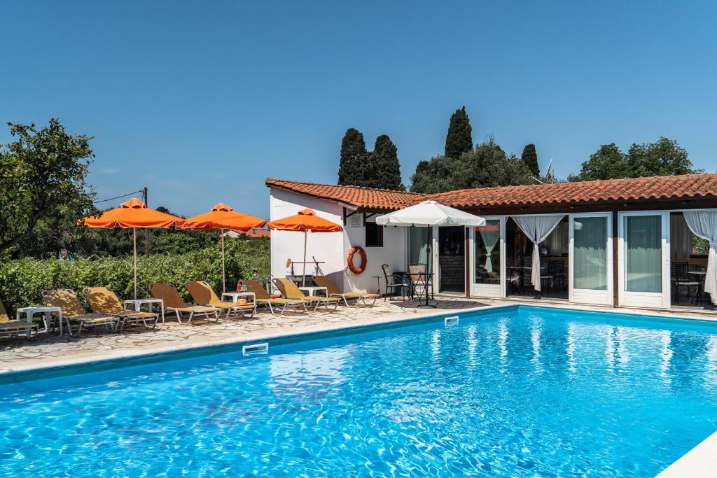 a swimming pool with chairs and umbrellas next to a house at Marketos studio 2 in Kefallonia