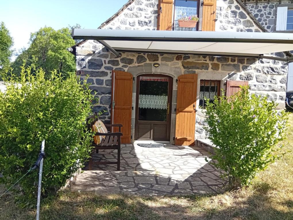 ein Steinhaus mit einer Holztür und einer Bank in der Unterkunft Tiny Cantalou in Saint-Martin-sous-Vigouroux