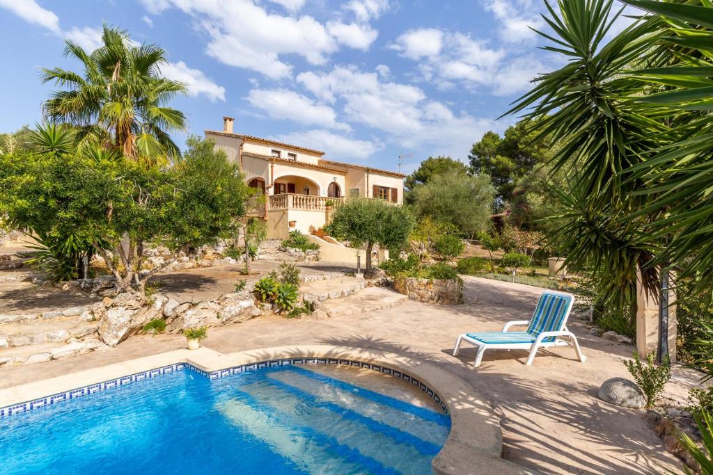 a house with a swimming pool and a blue chair at Sa Carbona in Artá
