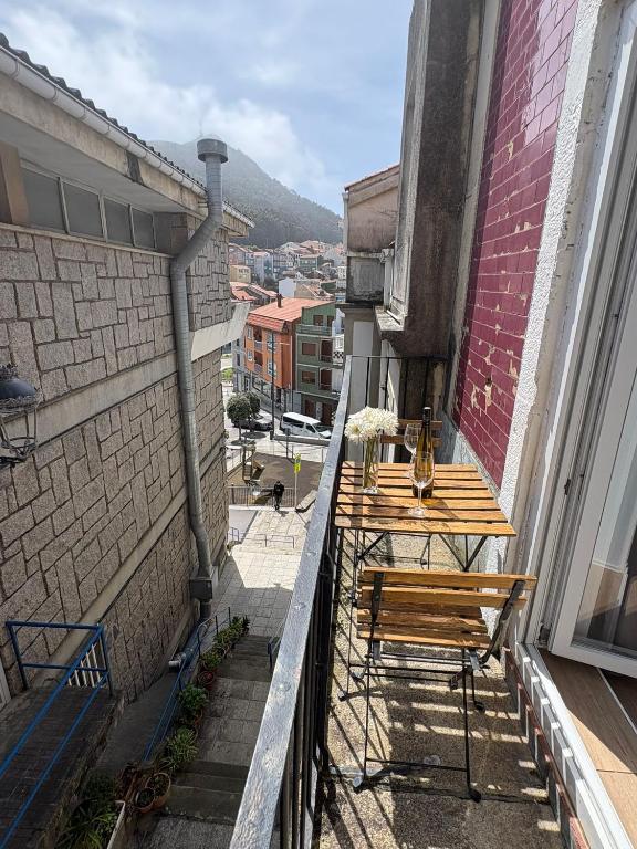 a balcony with a wooden table and bench on a building at Rincon del puerto I in A Guarda
