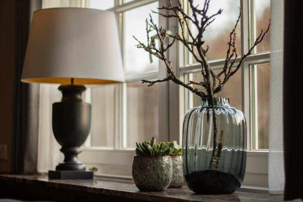 a table with a lamp and a vase with branches in it at Ferienhaus Hallmanns Hof in Schmallenberg