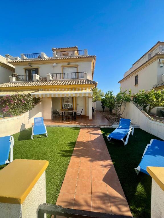 a yard with blue chairs and a house at Relax Inn in Pilar de la Horadada
