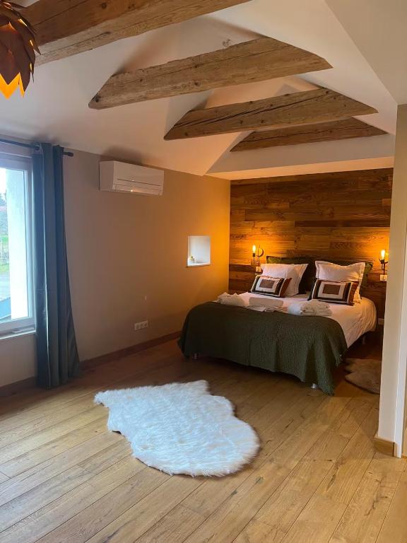 a bedroom with a large bed and a white rug at La Cure Vosgienne in Champdray
