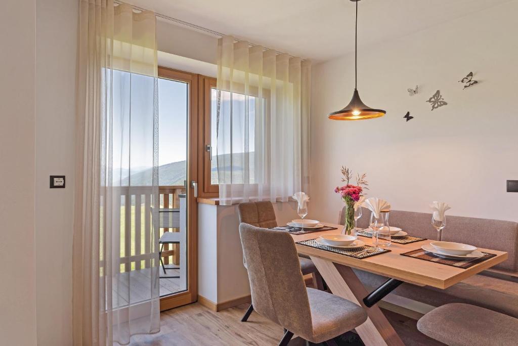 a dining room with a table and chairs and a balcony at Living Lerchna -Apartment Morgentau in Maranza