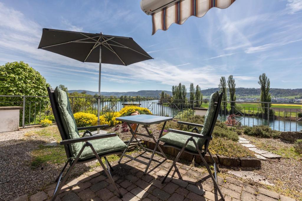 a table and two chairs with an umbrella at Ferienwohnung Rheinblick in Küssaberg