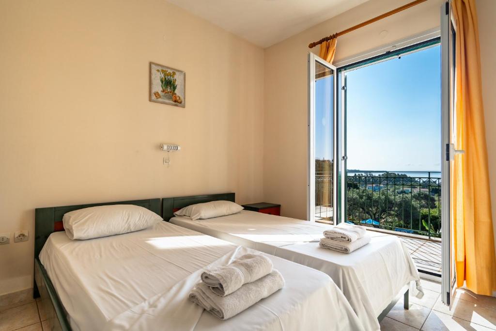 two beds in a room with a large window at Anemona apartment 2 in Kefallonia