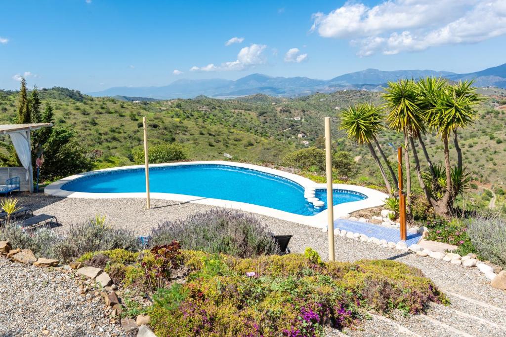 a swimming pool in a garden with mountains in the background at Finca Las Nuevas Casa Carmen in Alora