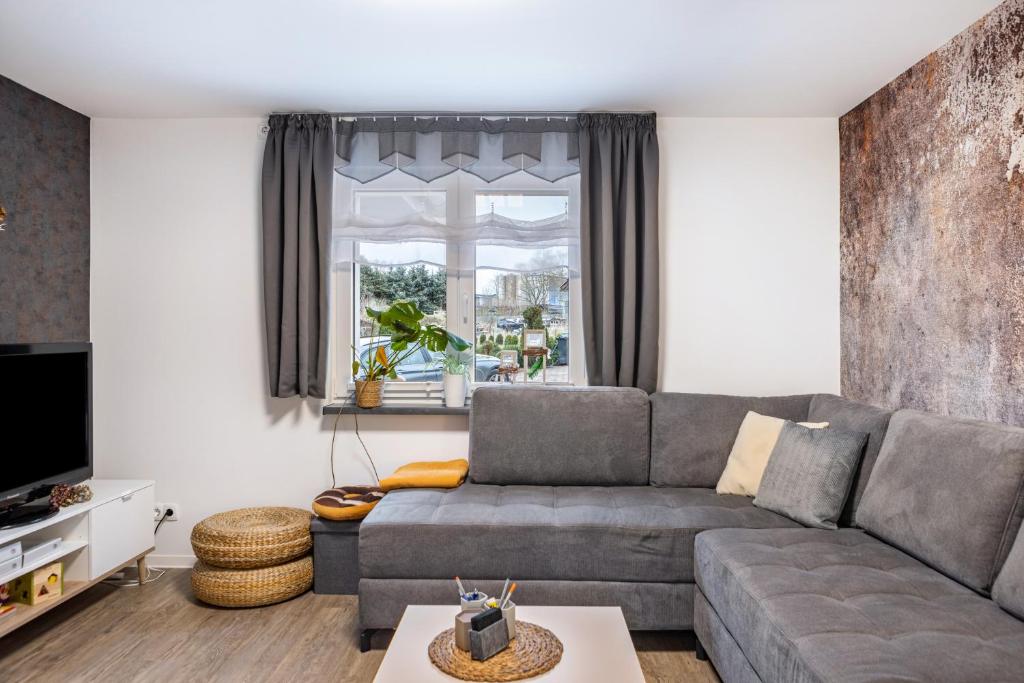 a living room with a gray couch and a window at Ferienhaus Kirsch in Blankenhain