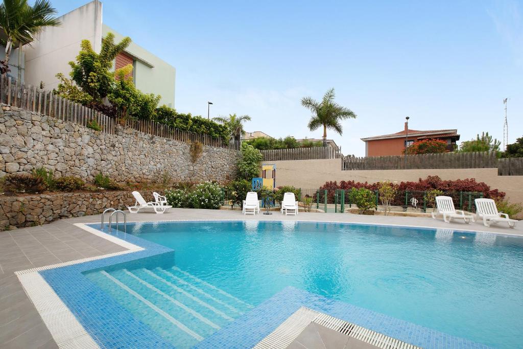 a large swimming pool with chairs and a building at La Quinta Adosado in Santa Úrsula