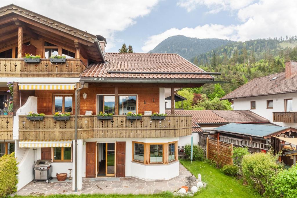 a house with a deck and mountains in the background at Alpblick Apartment Zugspitze in Garmisch-Partenkirchen