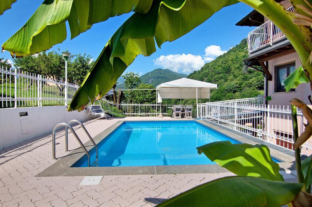 a swimming pool in front of a house with a mountain at Villa Adele in Gravedona