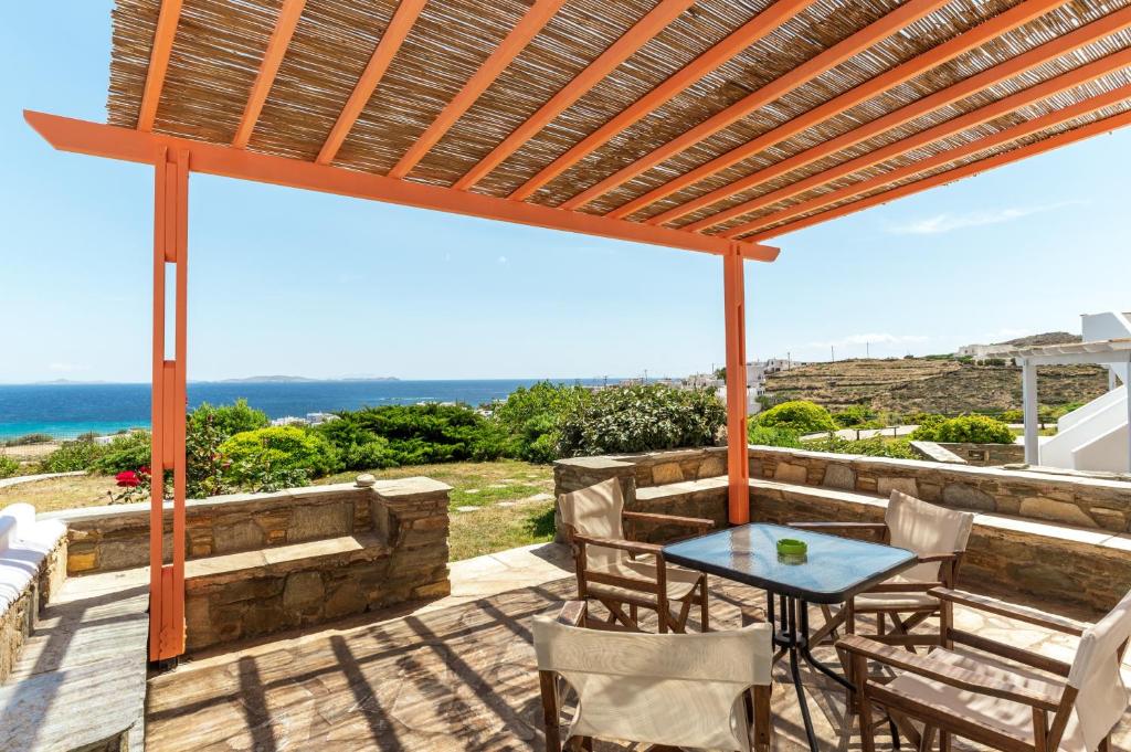 a patio with a table and chairs and the ocean at Anemologio 203 Tinos in Agios Ioannis