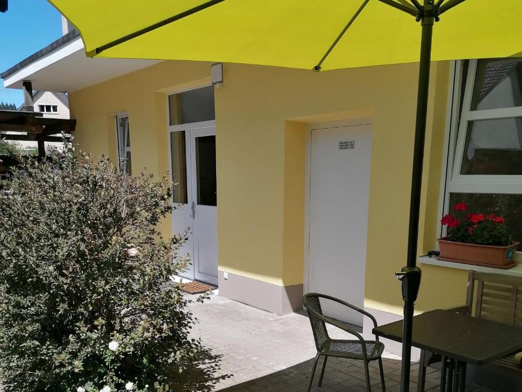 a yellow house with a table and chairs and an umbrella at Jogis Ferienwohnungen in Freiburg im Breisgau