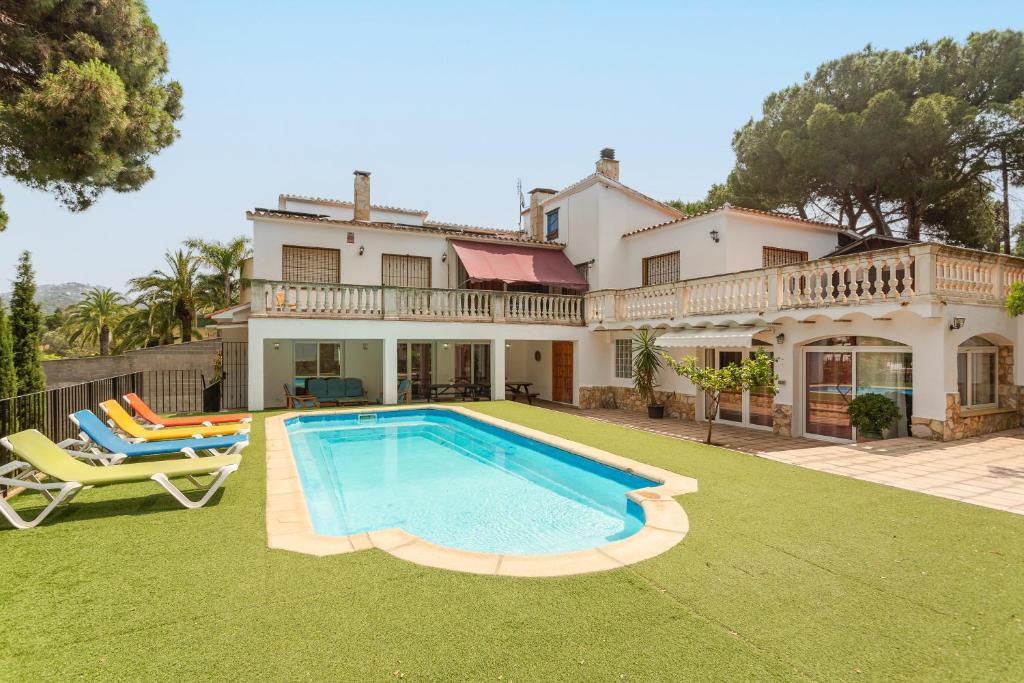 a house with a swimming pool in front of a yard at Allotjament Bogues in Lloret de Mar