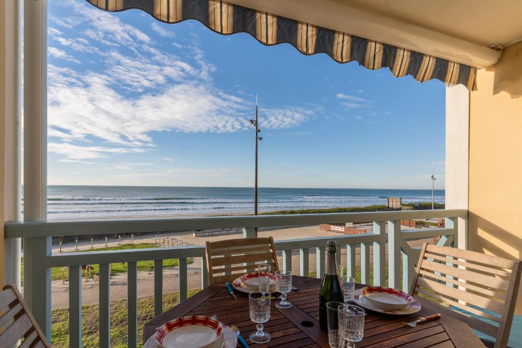 a table on a balcony with a view of the beach at Appartement Première ligne plage in Mimizan