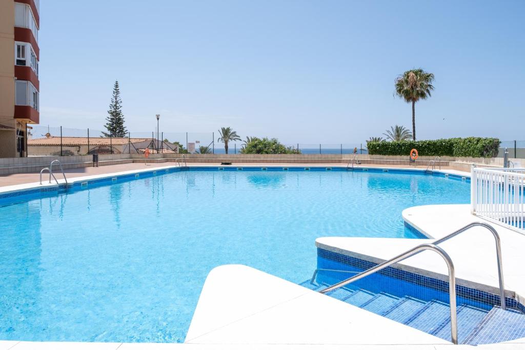 a large swimming pool with blue water at Beachfront Bungalow in Torrox Costa