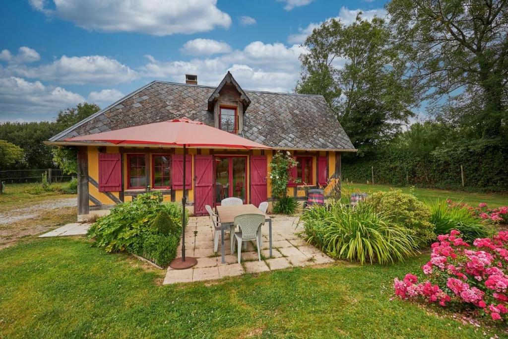 a red house with a table and chairs in the yard at La Cidrerie in Cresseveuille