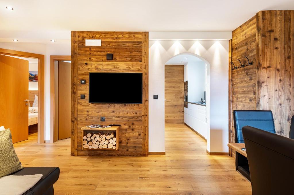 a living room with a wooden wall with a flat screen tv at Wegscheiderhof Apt Gartenwohnung in Velturno