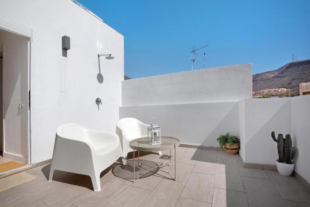 a dining room with white chairs and a table at Penthouse 3A in Morro del Jable