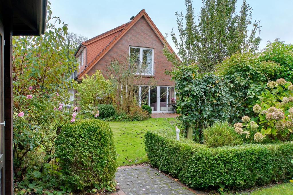 a house with a garden with bushes and trees at Ferienhaus Poth in Wangerland