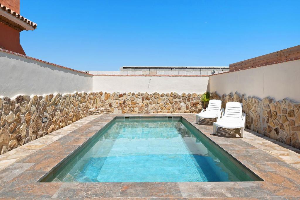 a swimming pool with two chairs next to a wall at Casa Juana Madera in Zahora