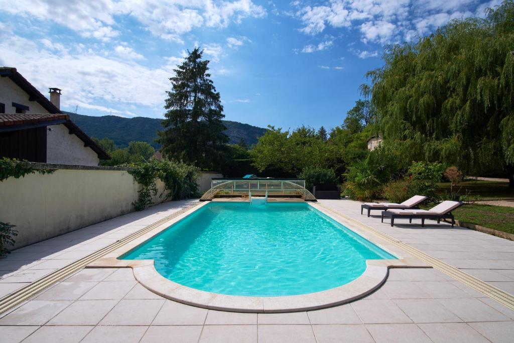 a swimming pool in a backyard with two lounge chairs at Villa De Marchi in Saint-Just-de-Claix
