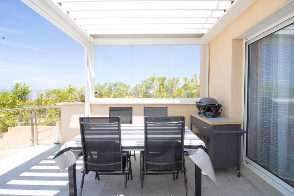a dining room with a table and chairs on a balcony at Superbe Appart Neuf Climatisé in Albitreccia