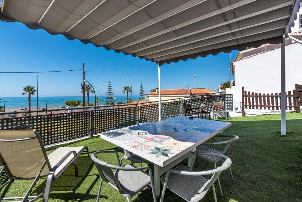 a patio with a table and chairs and the ocean at Apartamento a pie de playa in Benajarafe