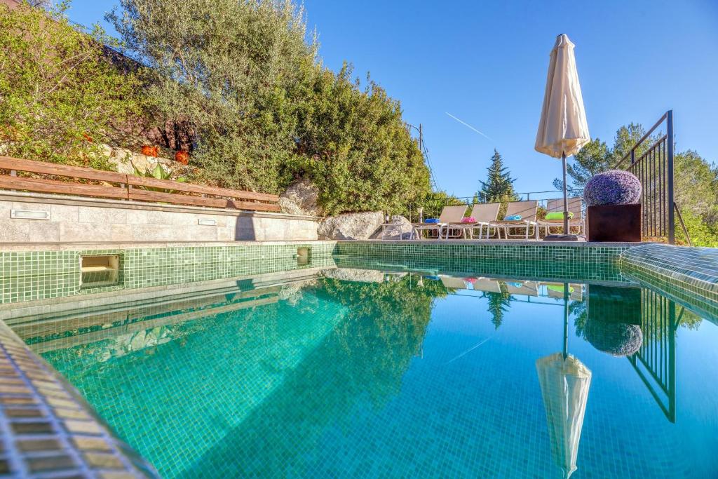 a swimming pool with an umbrella and a table at Miravall in Puigpunyent