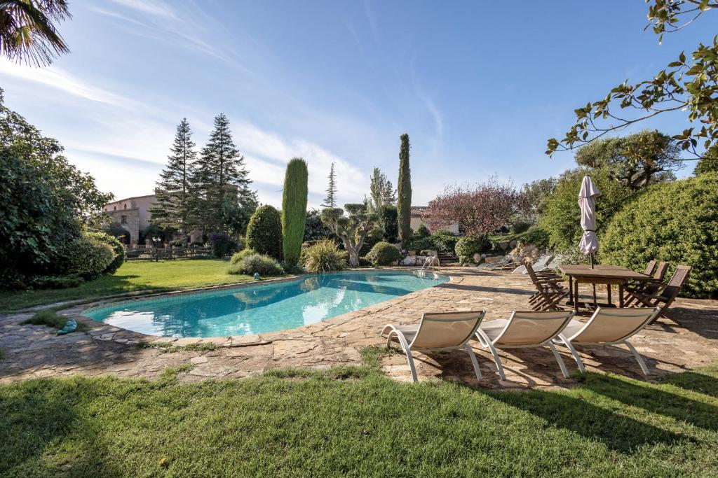 a swimming pool in a yard with chairs and a table at La Masia in El Bruc