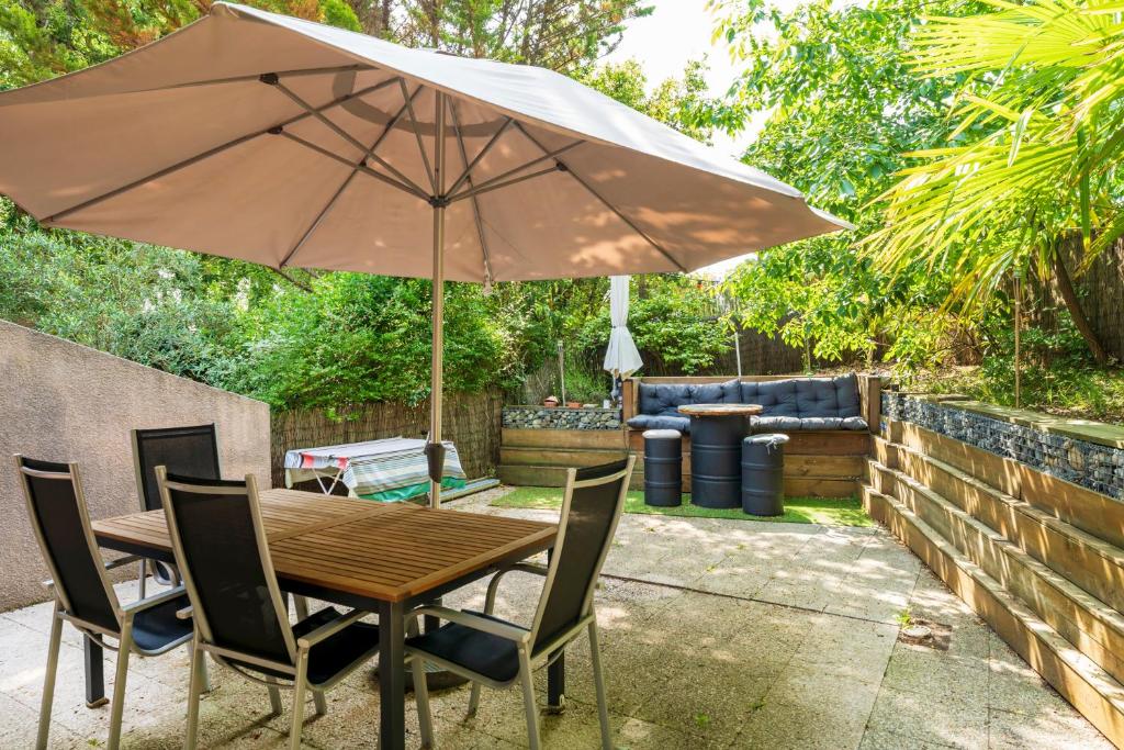 a wooden table and chairs with an umbrella at Maison Chaleureuse Avec Terrasse in Capbreton