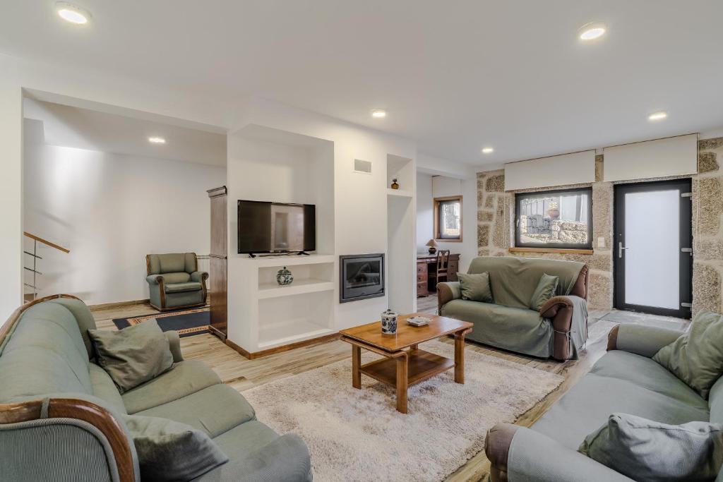 a living room with two couches and a tv at Casa Vilarinha Gerês in Bouro