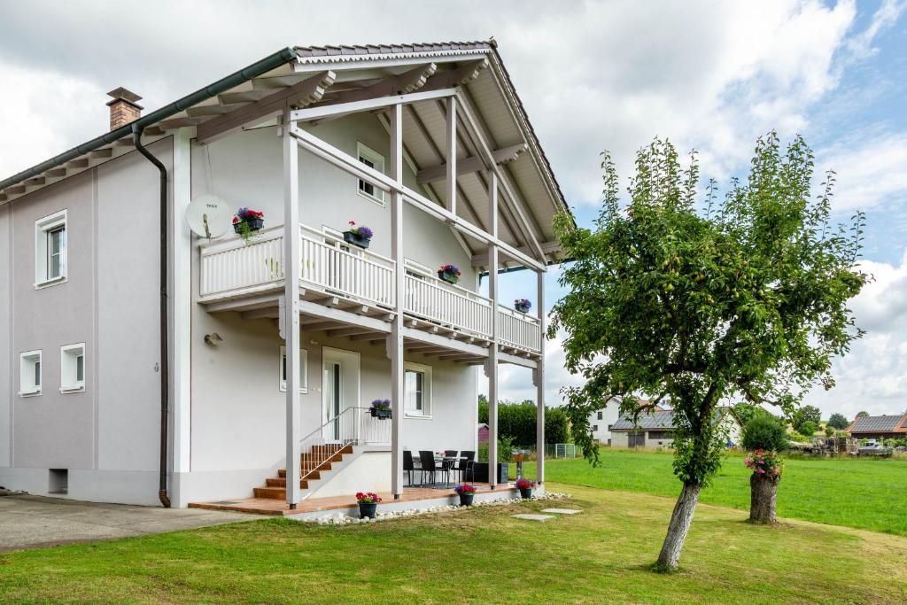 a white building with a balcony and a tree at Ferienwohnungen Mayerhofer in Arnstorf