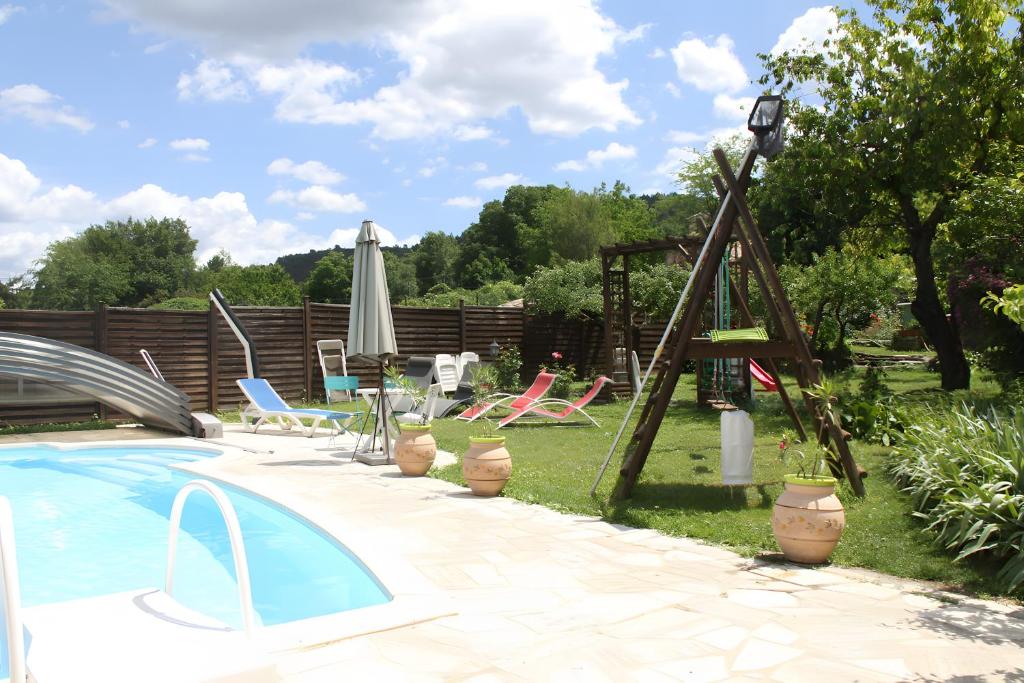 a swimming pool in a yard with chairs and an umbrella at Gîte De Diane in Allemagne-en-Provence