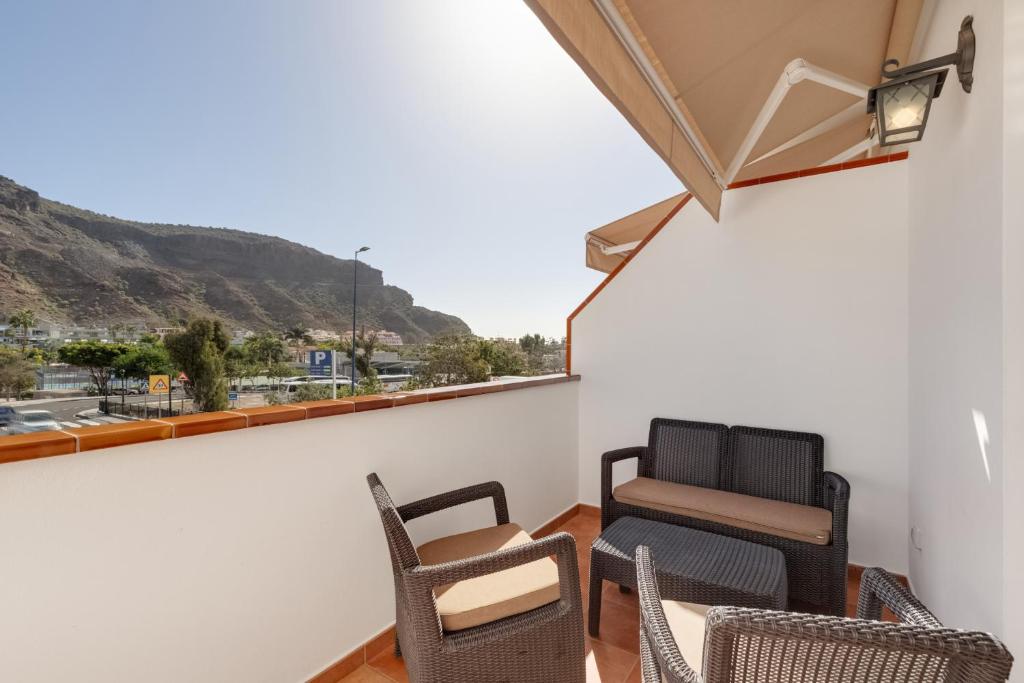 a balcony with chairs and a view of a mountain at Vv Estrella in Puerto de Mogán