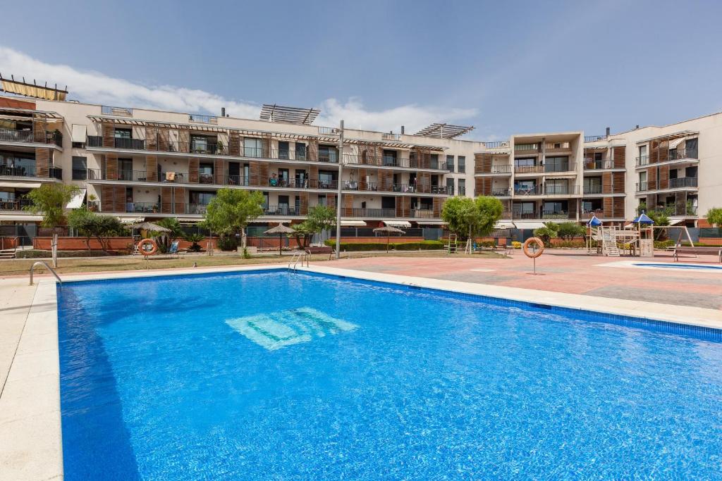 a large blue swimming pool in front of a building at Cubelles mar in Cubelles