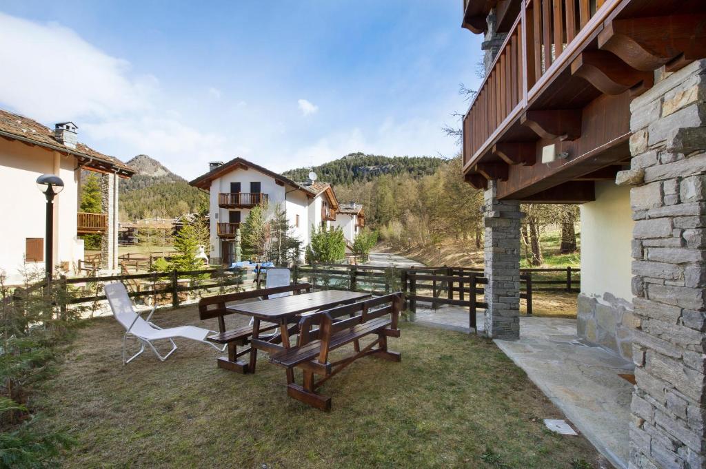a patio with a wooden table and chairs on the grass at Gioiello Col de Joux in Saint Vincent