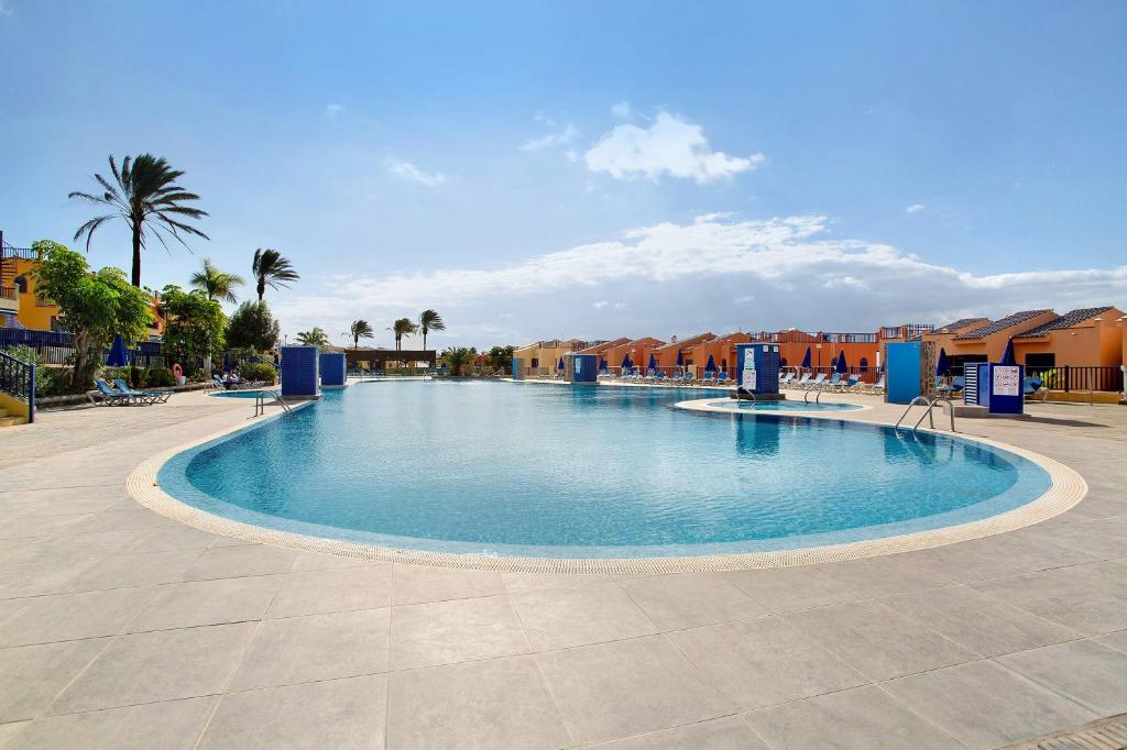 a large swimming pool in a resort with palm trees at Meloneras 1 in Maspalomas