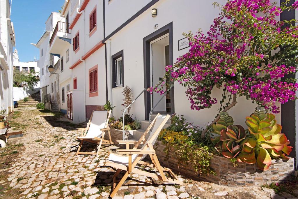 two chairs and a table in front of a building with flowers at Casa Barroca in Alte
