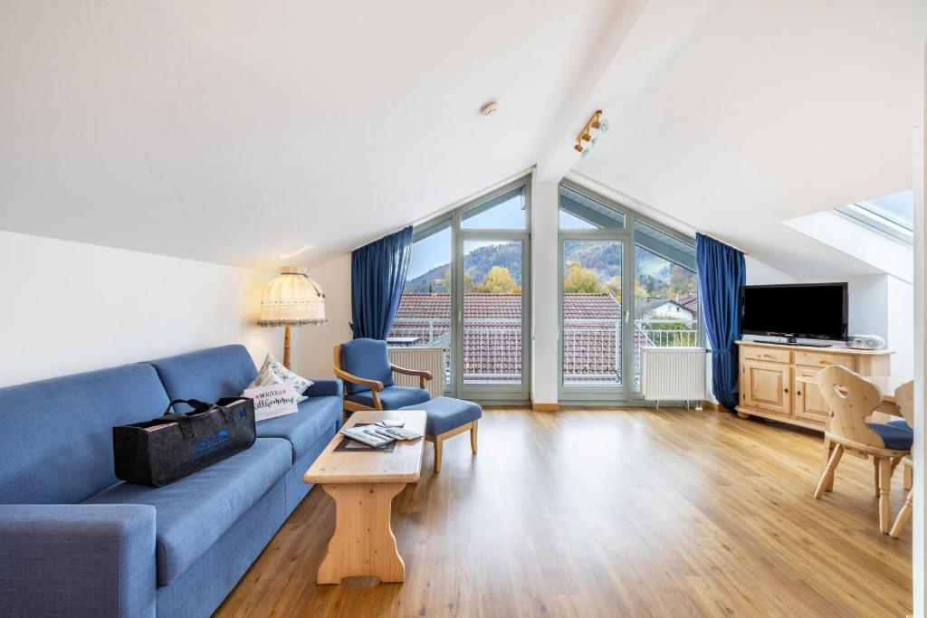 a living room with a blue couch and a large window at Fewo Brünnstein - Zimmer 65 in Oberaudorf