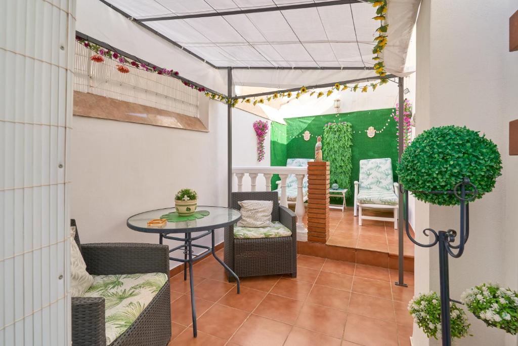 a patio with a table and chairs and a green wall at Naranja apartment in Nerja