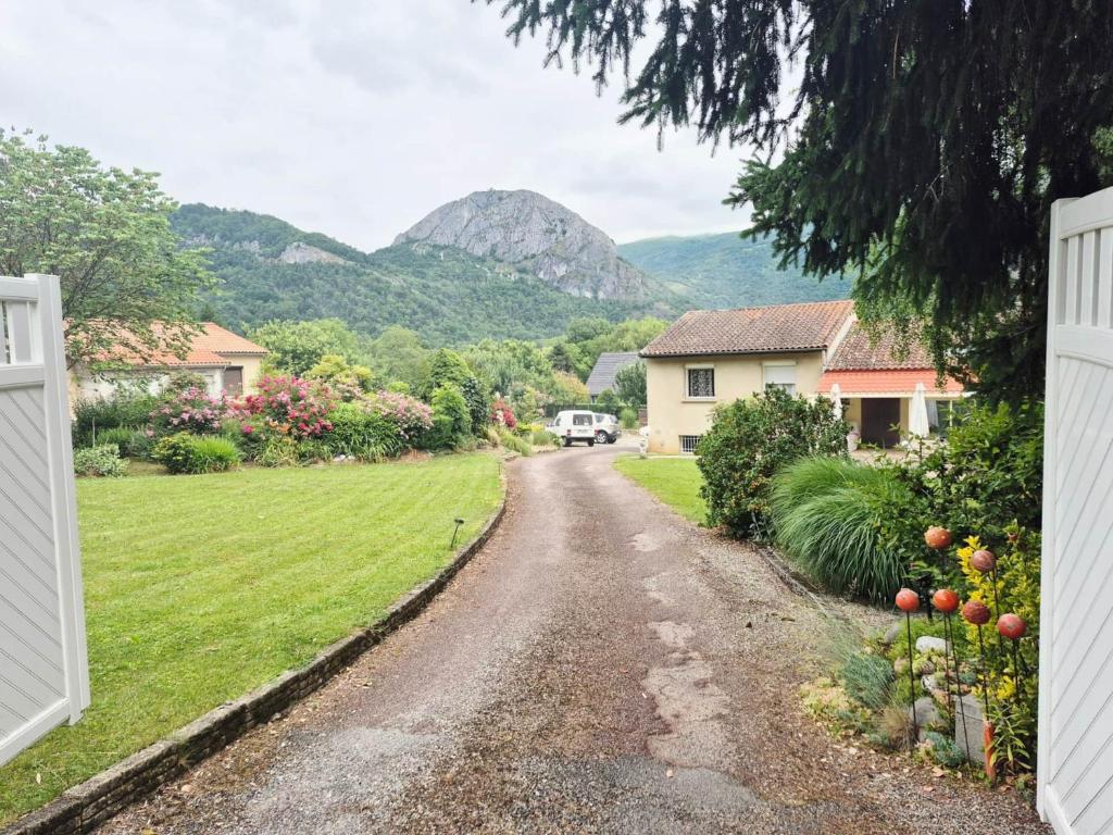 a road leading to a house with a mountain in the background at Gîtes le Clos des Pradals in Tarascon-sur-Ariège