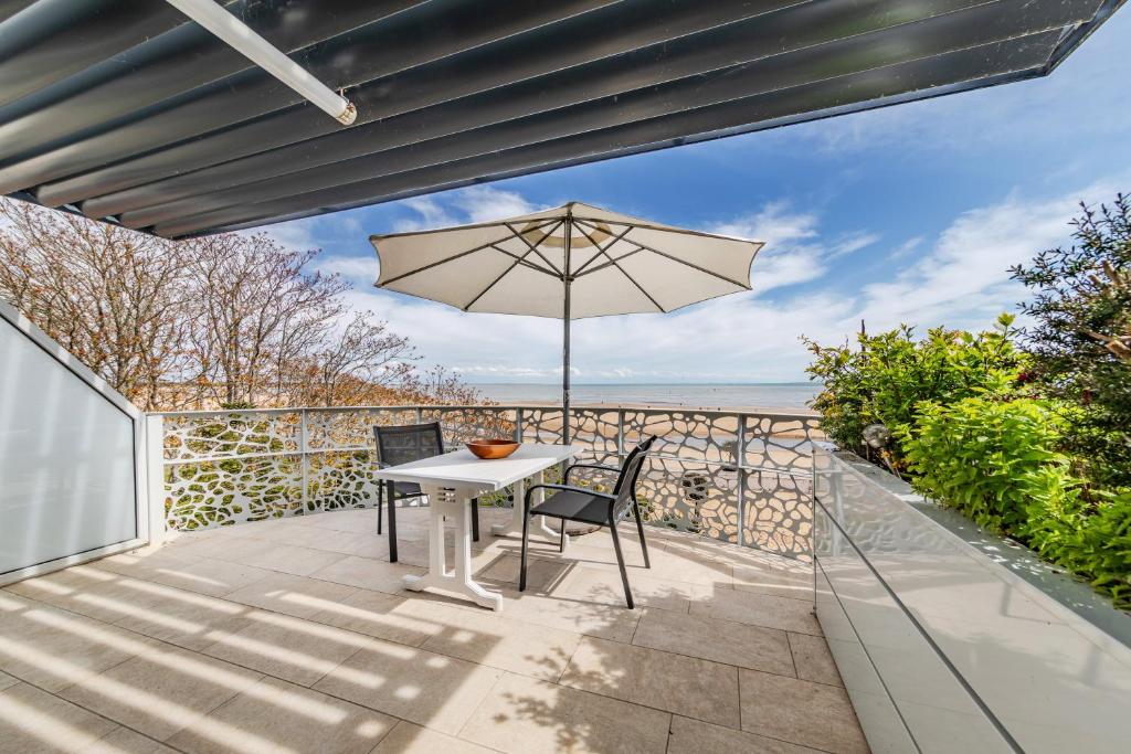 a patio with a table and chairs and an umbrella at Résidence Le Rêve Apt 209 in La Tranche-sur-Mer