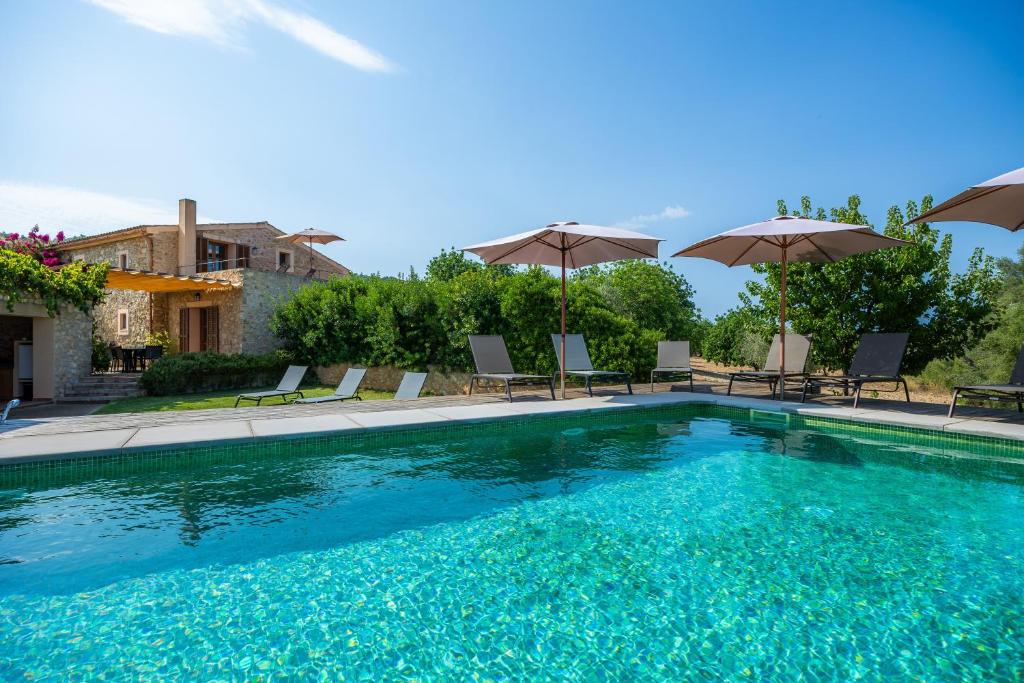 a large swimming pool with chairs and umbrellas at Els Clepes in Son Servera