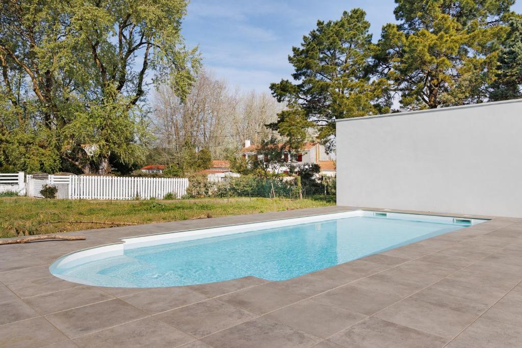 a swimming pool in a yard with a white wall at Chambres D'hôtes Sous Le Pin in Les Sables-d'Olonne