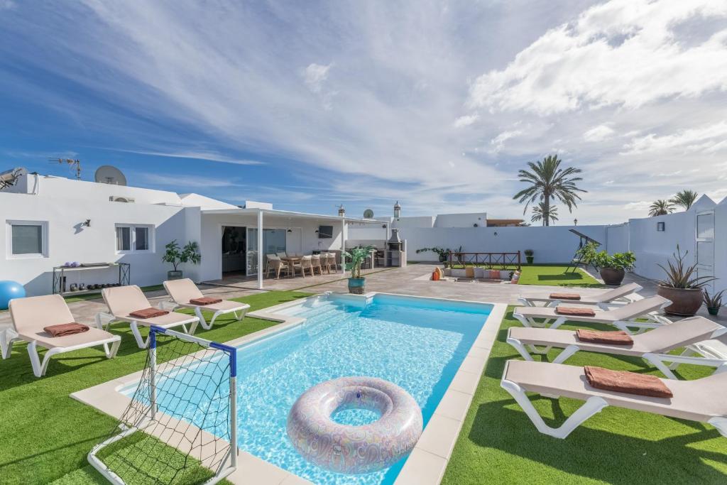 an outdoor swimming pool with chaise lounges and a swimming poolvisorvisor at The Suite Villa in Playa Blanca