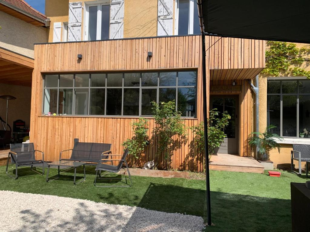 a house with two chairs and an umbrella in the yard at Maison du Bonheur, Gîtes in Le Pin