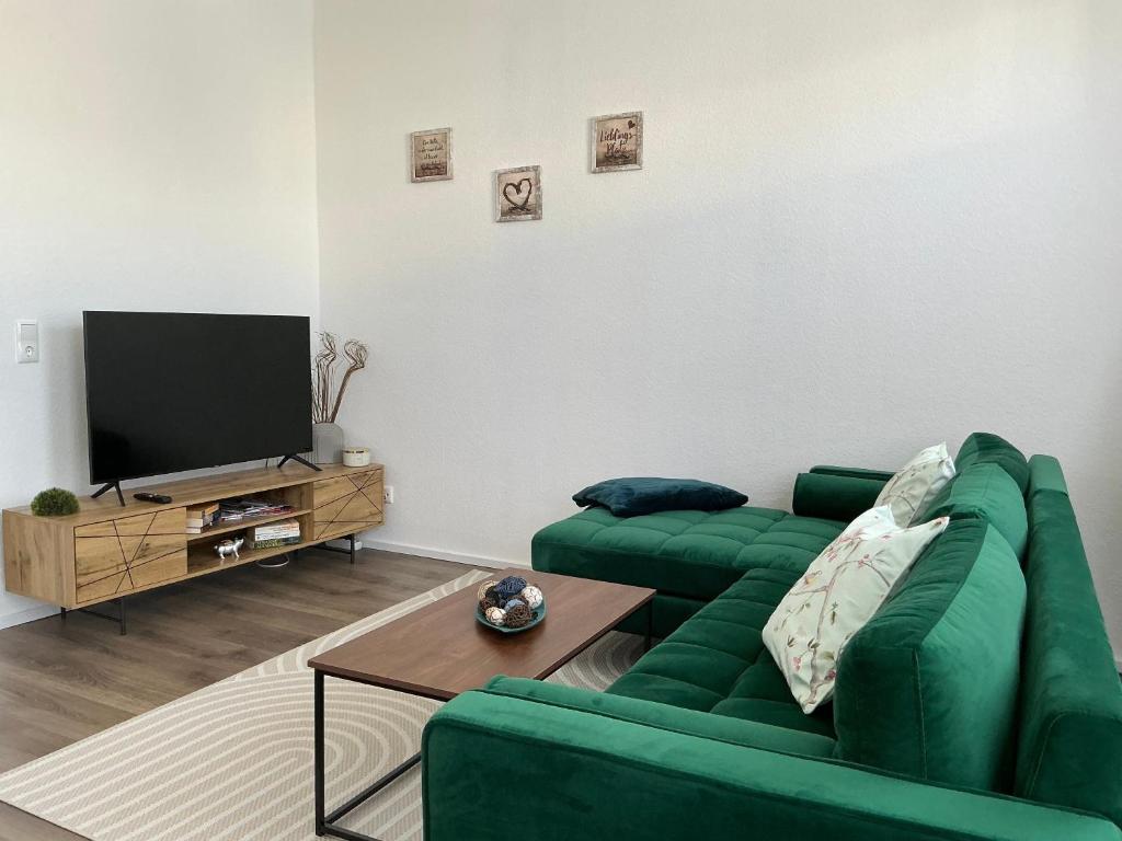 a living room with a green couch and a television at Harzträume Thale in Thale